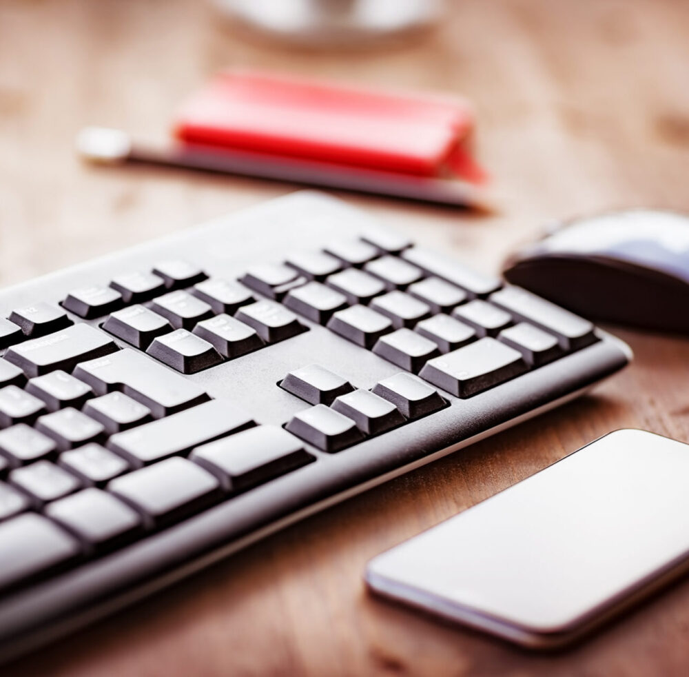 Desktop in the office, computer keyboard, pc mouse and mobile phone on the wooden table, work place